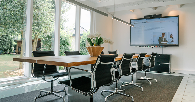 Moderner Besprechungsraum der Kanzlei Runde Glüsing Baune in Ibbenbüren mit großem Tisch, Stühlen und Smartboard