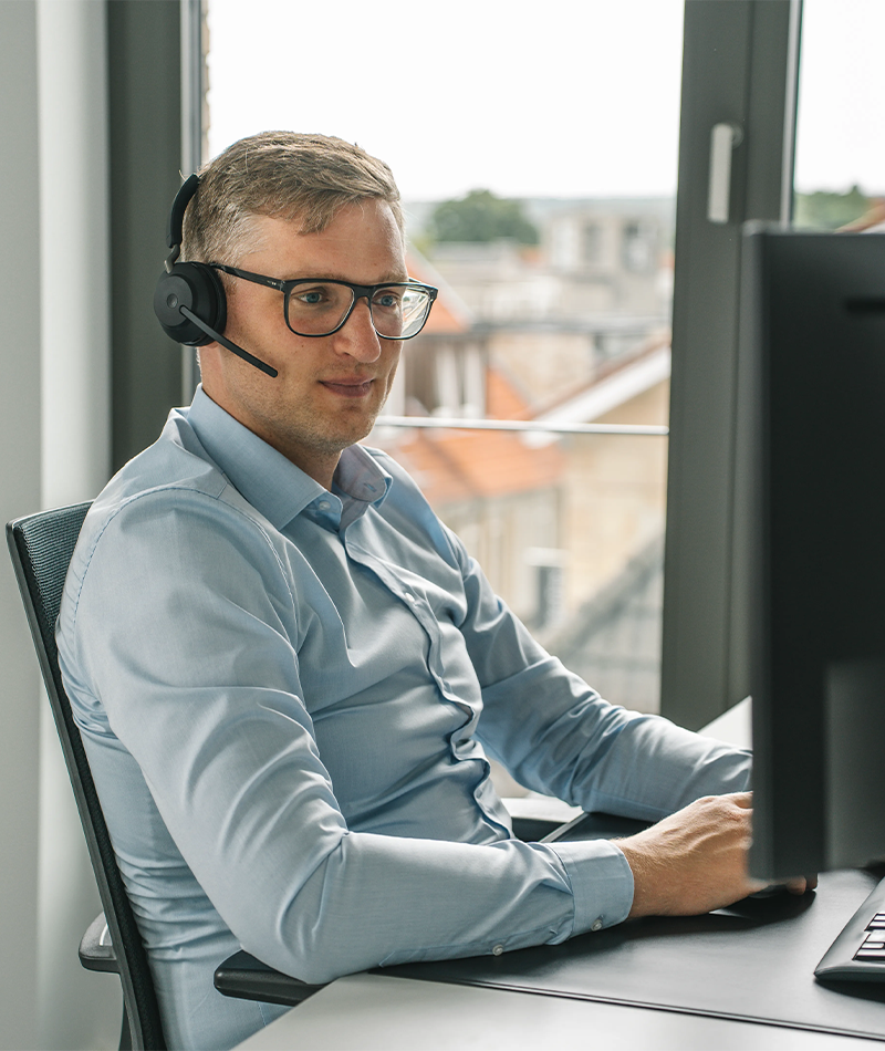Ein Partner der Steuerkanzlei Runde Glüsing Baune mit Headset bei der digitalen Beratung am Schreibtisch vor dem Bildschirm