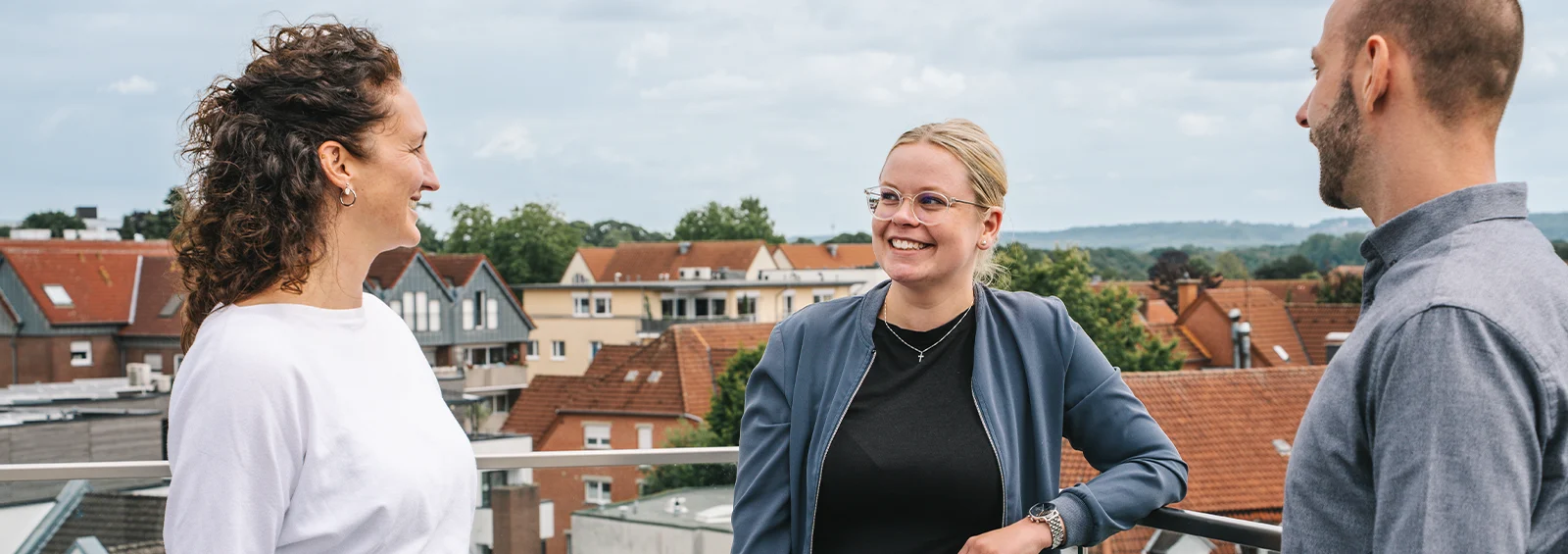 Drei Kollegen der Kanzlei Runde Glüsing Baune im Gespräch auf einer Dachterrasse mit Blick über die Stadt
